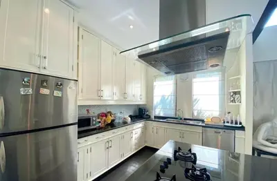 a kitchen with white cabinets and a stainless steel refrigerator at Pool Villa - 3 Bedroom- Walking to Bangtao Beach, Restaurants and Supermarkets in Bang Tao Beach