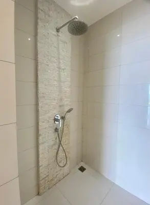 a shower in a white tiled bathroom at The View Luxury Condominium Karon in Kata Beach