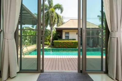 an open sliding glass door to a swimming pool at 3 bedrooms private villa with garden Rawai in Phuket Town