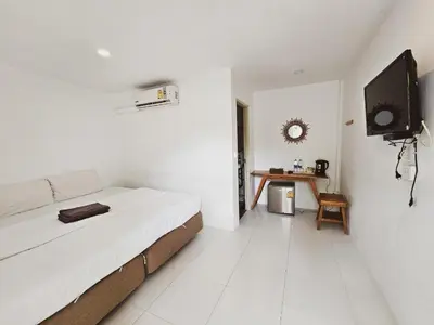 a white bedroom with a bed and a tv on a wall at BB Hidden House in Phi Phi Don
