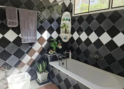 a bathroom with a tub and black and white tiles at Grand Luxe Kamala in Kamala Beach