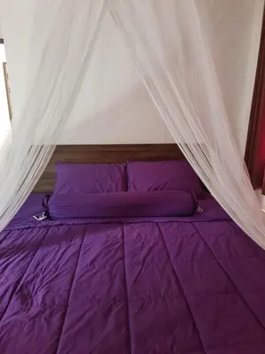 a bed with purple sheets and a canopy at Grand Luxe Kamala in Kamala Beach