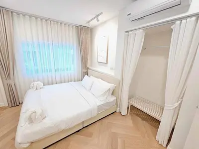 a white bedroom with a bed and a window at Baan 112 Patong in Patong Beach