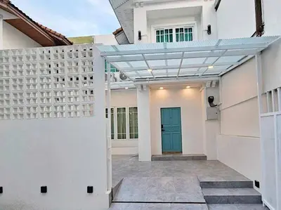 a white house with a blue door and a building at Baan 112 Patong in Patong Beach