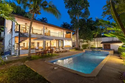 a villa with a swimming pool in front of a house at Coconut Palms huge swimming pool and pool table V136 in Rawai Beach