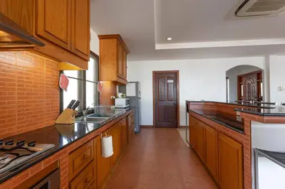 a large kitchen with wooden cabinets and a counter top at Coconut Palms huge swimming pool and pool table V136 in Rawai Beach