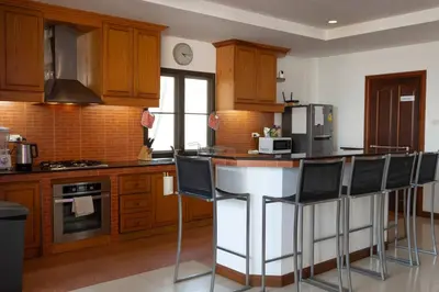 a kitchen with wooden cabinets and a bar with chairs at Coconut Palms huge swimming pool and pool table V136 in Rawai Beach