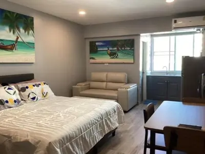 a bedroom with a bed and a couch and a table at Patong Vacation Condos by Pam - 28 SQM modern condos with private bathroom, kitchen, King Bed, free WiFi and 65 inch smart TC in Patong Beach