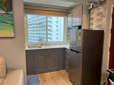 a kitchen with a stainless steel refrigerator and a window at Patong Vacation Condos by Pam - 28 SQM modern condos with private bathroom, kitchen, King Bed, free WiFi and 65 inch smart TC in Patong Beach