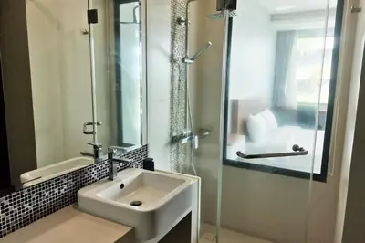 a bathroom with a sink and a glass shower at At the Tree bright studio by Lofty in Rawai Beach