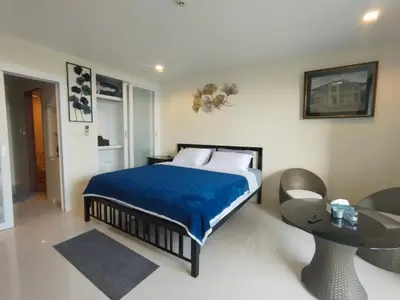 a bedroom with a bed with a blue blanket and a table at The Pixel Cape Panwa Beach Condo in Panwa Beach
