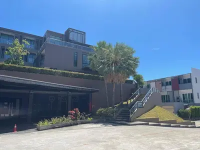 a building with stairs and palm trees in front of it at The Pixel Cape Panwa Beach Condo in Panwa Beach
