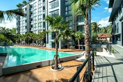 a swimming pool with palm trees in front of a building at Citygate serviced apartments Kamala beach, rooftop pool and gym P311 in Kamala Beach