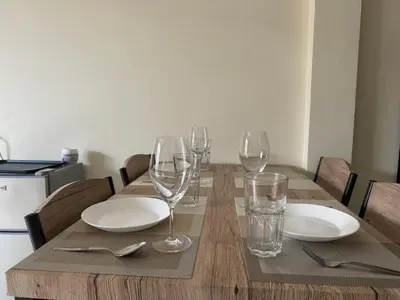 a wooden table with plates and wine glasses on it at Apartments Kata Beach in Kata Beach