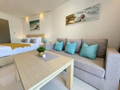 a living room with a couch and a bed at Cozy Studio Rawai Beach Phuket in Ban Saiyuan (1)