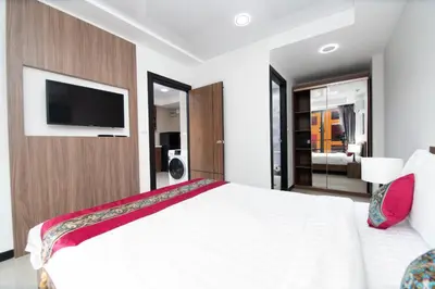 a bedroom with a large white bed with a flat screen tv at Nai Harn Beach Condominimum in Phuket Town