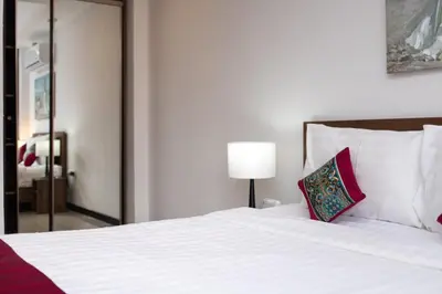 a bedroom with a large white bed with red pillows at Nai Harn Beach Condominimum in Phuket Town