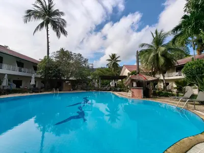a person swimming in a large blue swimming pool at V Beach Resort in Patong Beach