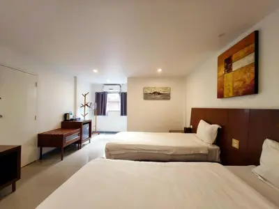 a hotel room with two beds and a desk at V Beach Resort in Patong Beach