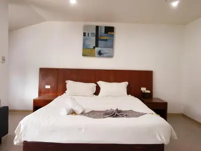 a bedroom with a large white bed with a wooden headboard at V Beach Resort in Patong Beach