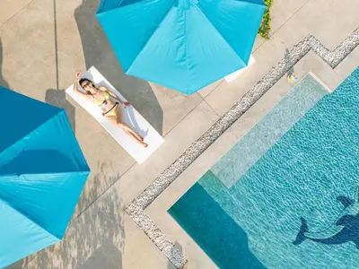 an overhead view of two people in a pool with blue umbrellas at Phuket 4-6 Bedroom Seaview Villa Infinity 25mPool In-Villa Dining & Butler Gym in Thalang