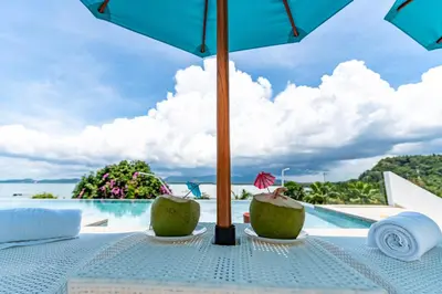a table with an umbrella next to a pool at Phuket 4-6 Bedroom Seaview Villa Infinity 25mPool In-Villa Dining & Butler Gym in Thalang