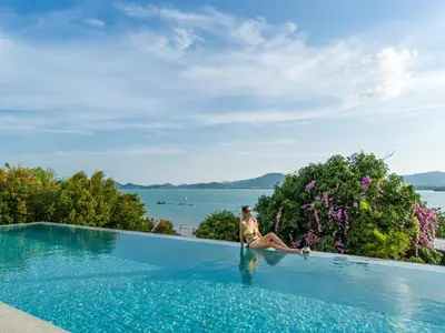 a woman sitting on the edge of a swimming pool at Phuket 4-6 Bedroom Seaview Villa Infinity 25mPool In-Villa Dining & Butler Gym in Thalang