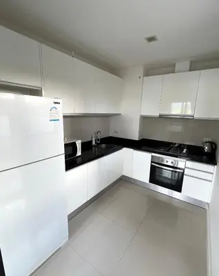 a white kitchen with white cabinets and a refrigerator at Happy House in Laguna Park in Laguna Phuket