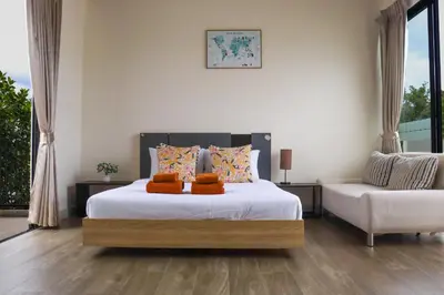 a bedroom with a large bed and a chair at Happy House in Laguna Park in Laguna Phuket