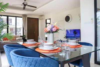a dining room with a glass table and blue chairs at Happy House in Laguna Park in Laguna Phuket