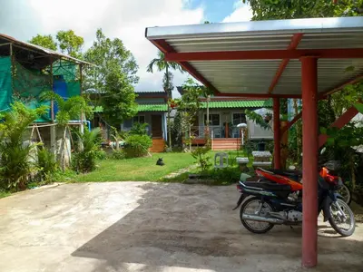 a motorcycle parked under a roof in front of a house at Bonus Bungalow in Chalong