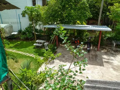 a garden with a bench and a blue roof at Bonus Bungalow in Chalong