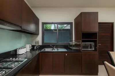 a kitchen with wooden cabinets and a sink and a window at Villa Bulan with 3BR with Yoga house Nai Harn in Rawai Beach