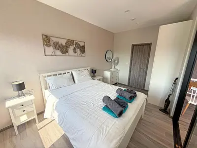 a bedroom with a large white bed with towels on it at The Title Residencies Naiyang by Mill in Nai Yang Beach