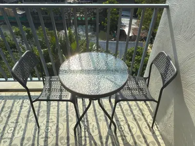 a glass table and two chairs on a balcony at The Title Residencies Naiyang by Mill in Nai Yang Beach