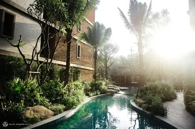 a swimming pool in front of a building with palm trees at The Title Residencies Naiyang by Mill in Nai Yang Beach