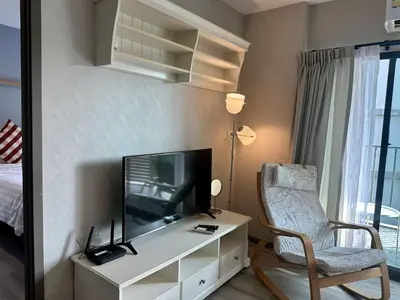 a living room with a tv and a chair at The Title Residencies Naiyang F by Mill in Nai Yang Beach
