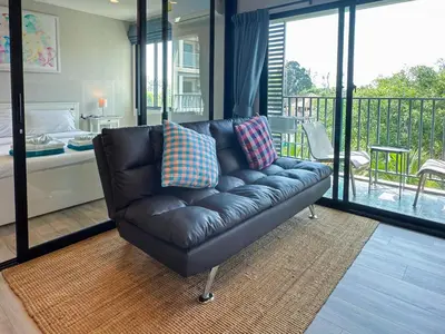 a leather couch in a living room with a balcony at The Title Residencies Naiyang F by Mill in Nai Yang Beach