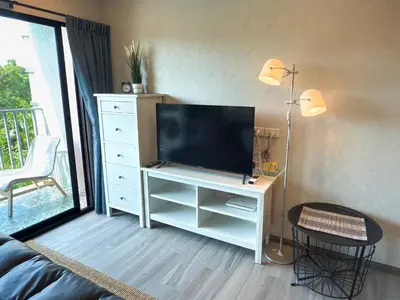 a living room with a television on a white dresser at The Title Residencies Naiyang F by Mill in Nai Yang Beach