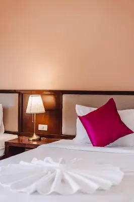 a bedroom with a large white bed with a red pillow at Bauman-Ville Hotel Patong in Patong Beach