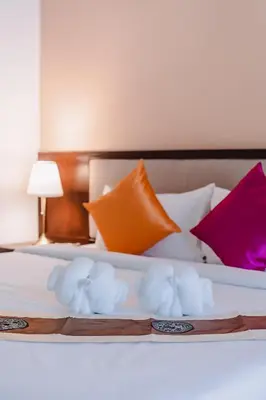 a white bed with colorful pillows on it at Bauman-Ville Hotel Patong in Patong Beach