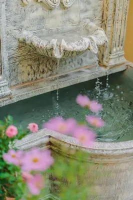 a water fountain with pink flowers in the foreground at Bauman-Ville Hotel Patong in Patong Beach