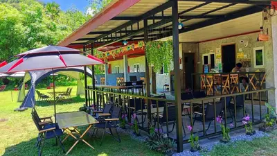 a patio with an umbrella and tables and chairs at Mukda in Ko Yao Noi