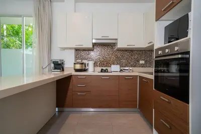 a kitchen with white cabinets and wooden counters at Bangtao villa 3 bedroom in Phuket Town