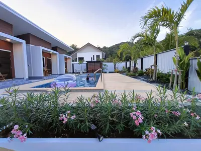 a house with a swimming pool and some flowers at Hello Montri in Klong Muang Beach