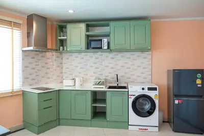a kitchen with green cabinets and a washing machine at Nature's Hideaway by Ratana, Rawai in Ban Saiyuan (1)