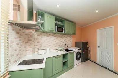 a kitchen with green cabinets and a washer and dryer at Nature's Hideaway by Ratana, Rawai in Ban Saiyuan (1)