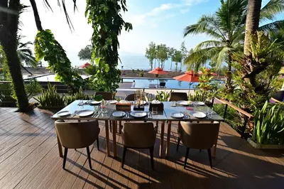 a table on a deck with a view of the ocean at Big Sun Residences By iRETREAT in Ko Yao Noi