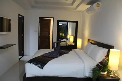 a bedroom with a large white bed with two lamps at The Seashore Kamala Service Apartment in Kamala Beach