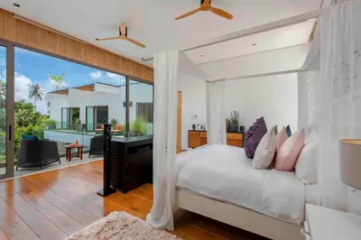 a bedroom with a large bed and a balcony at Villa White Skies in Khok Kloi
